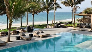 A poolside area with lounge chairs, a bar, and a view of the beach.
