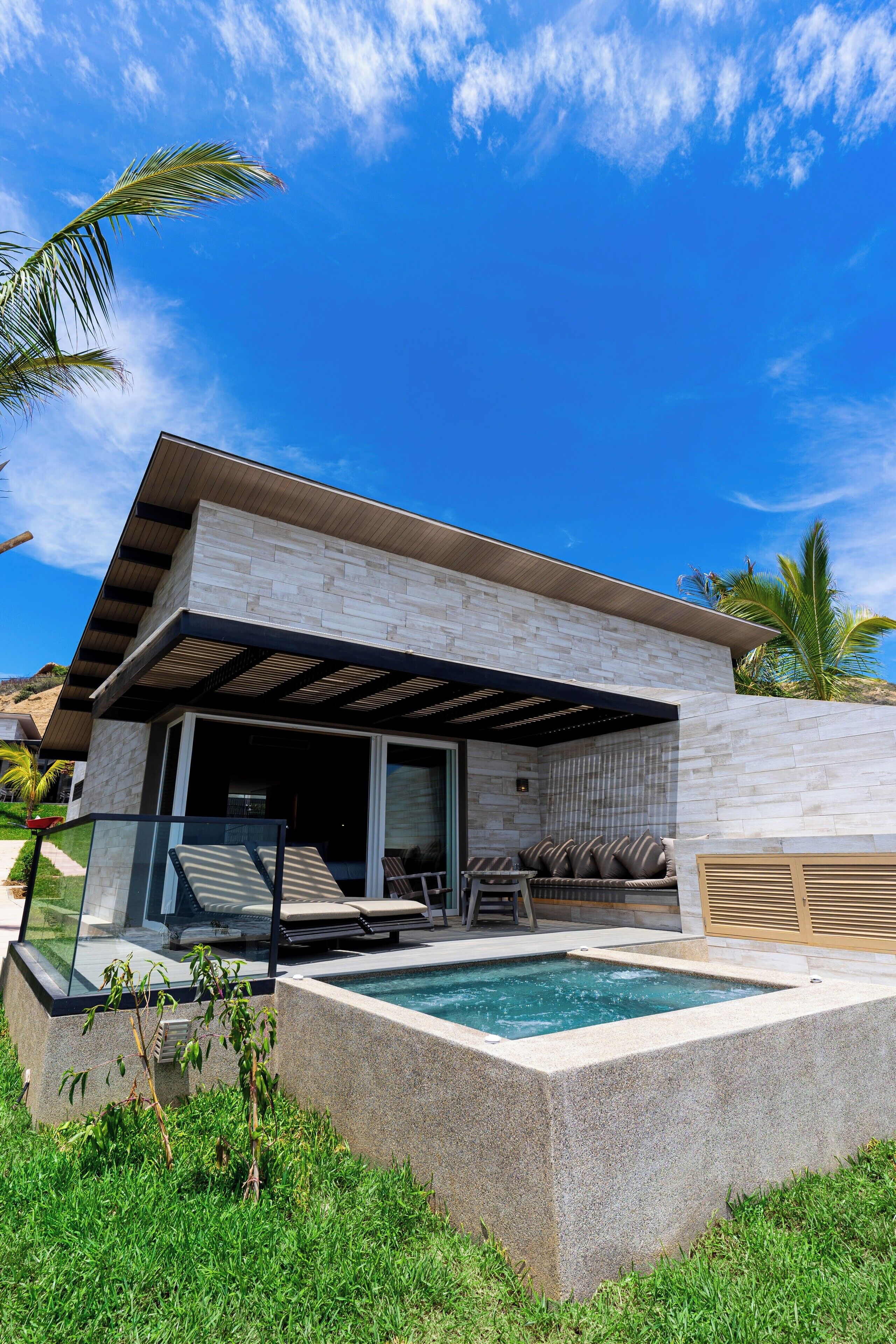 Una casa moderna con piscina, mobiliario de exterior y un porche cubierto.