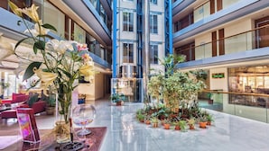 Un vaste atrium à plusieurs étages, doté de grandes fenêtres et agrémenté de plantes d’intérieur.