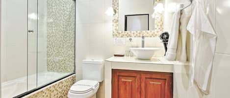 Un baño con cabina de ducha de vidrio, inodoro, lavabo con espejo y armarios de madera.