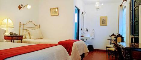 Een hotelkamer met twee bedden, een bureau, een stoel, een badkamer en een kroonluchter.