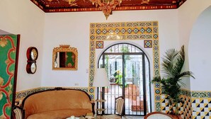 A room with a chandelier, a sofa, a chair, a mirror, and a decorative archway. - Hotel de Su Merced (Sucre)