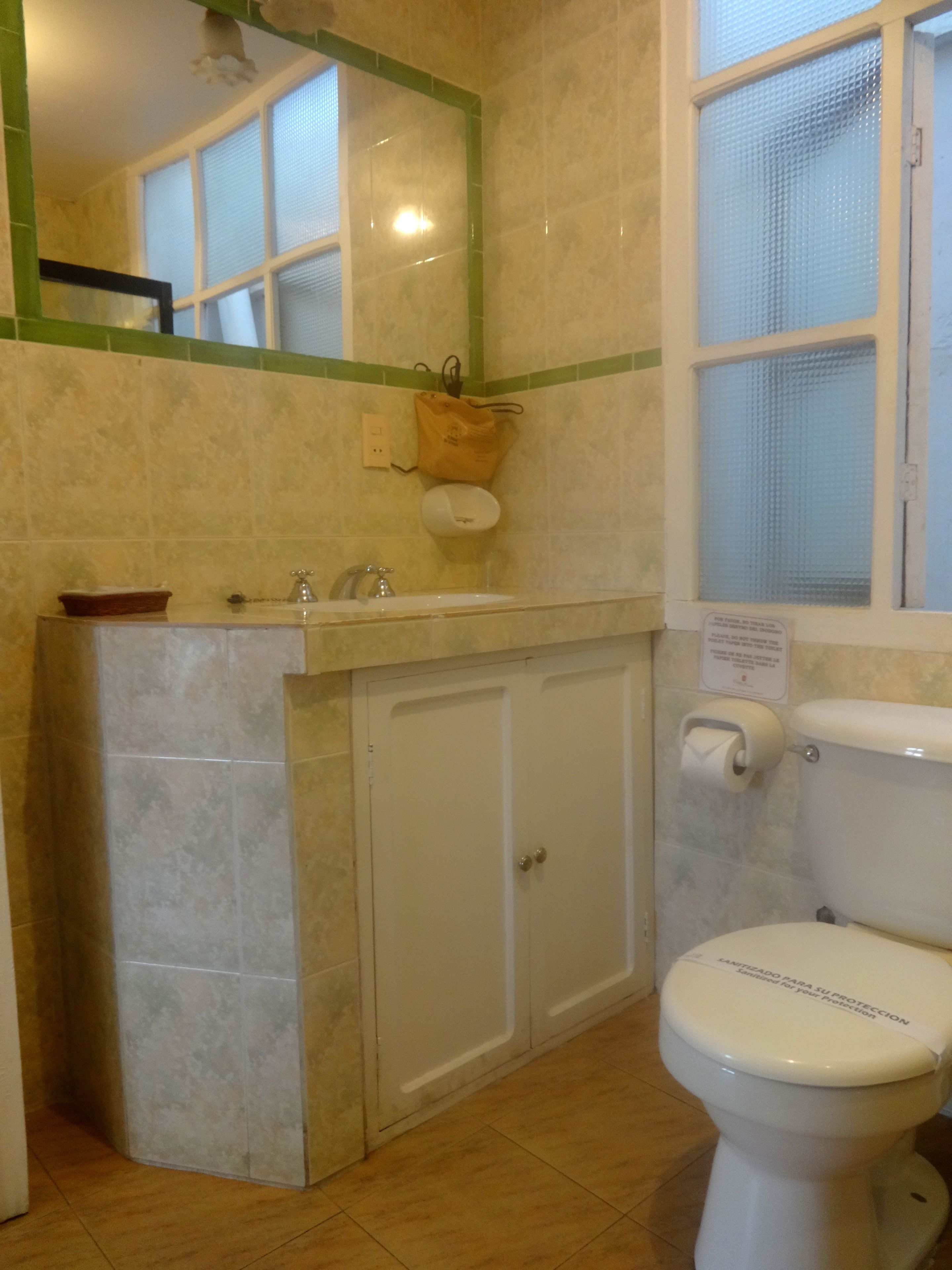 A bathroom with a toilet, sink, and mirror.