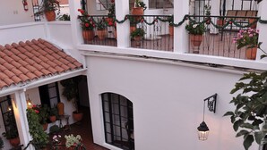 A multi-level courtyard with terracotta-tiled roofs, potted plants, and a central fountain. - Hotel de Su Merced (Sucre)
