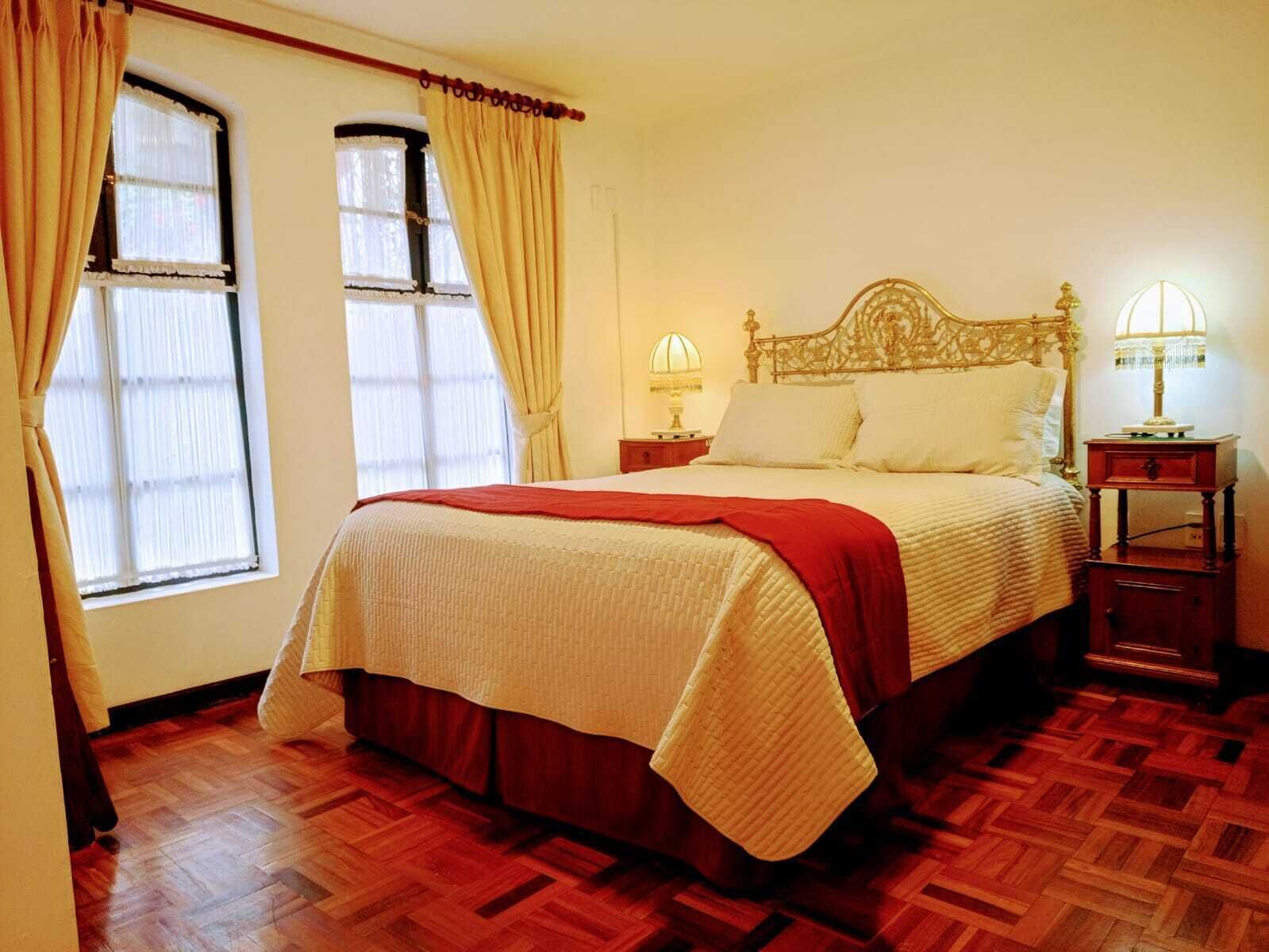 A bedroom with a bed, two bedside tables, a window, and a door.