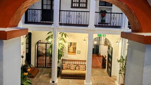 A courtyard with a bench, potted plants, and a gate. - Hotel de Su Merced (Sucre)