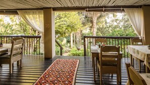 A covered outdoor seating area with wooden furniture and a patterned rug. - Lidiko Lodge (St. Lucia)