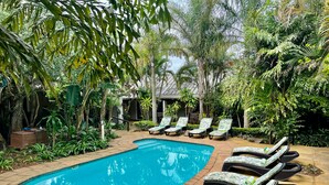 A pool area with lounge chairs and lush greenery. - Lidiko Lodge (St. Lucia)