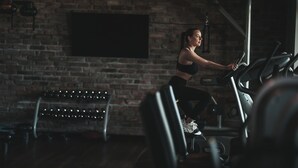 A person using a stationary bike in a gym with brick walls and a large screen. - Hotel Remes (Opalenica)