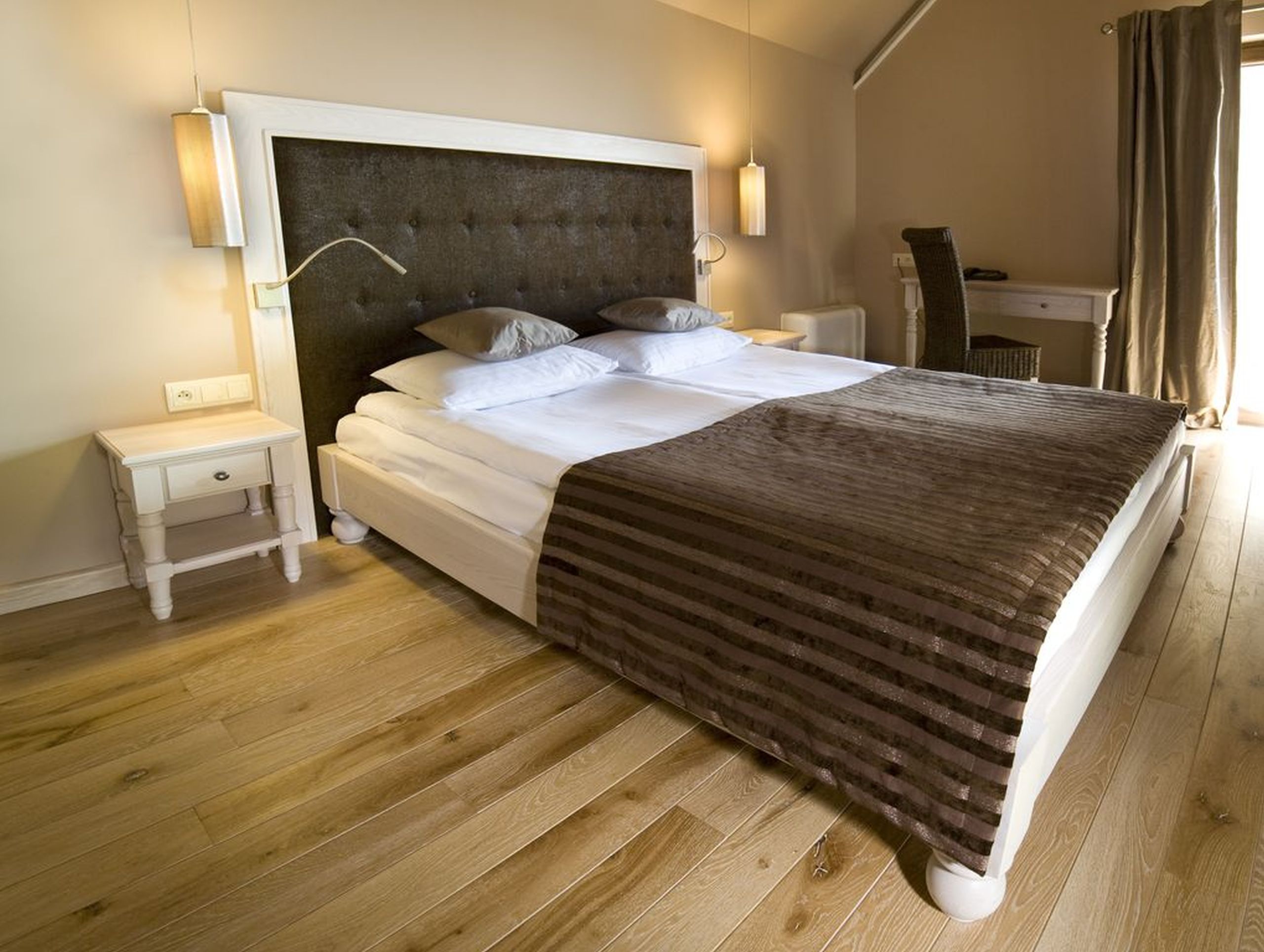 Un dormitorio con una cama grande, una mesita de noche y una lámpara.
