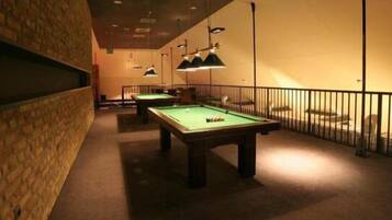 A pool table in a room with brick walls and a railing.