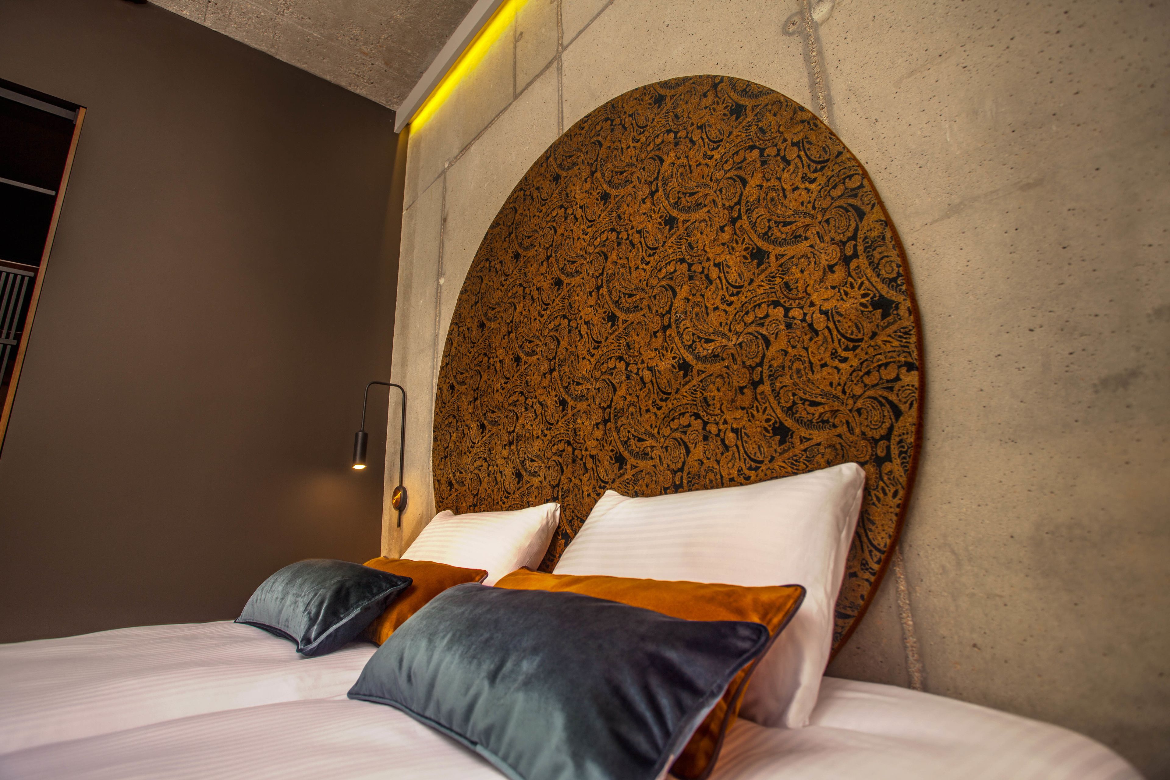 A bed with multiple pillows and a large, ornate headboard.