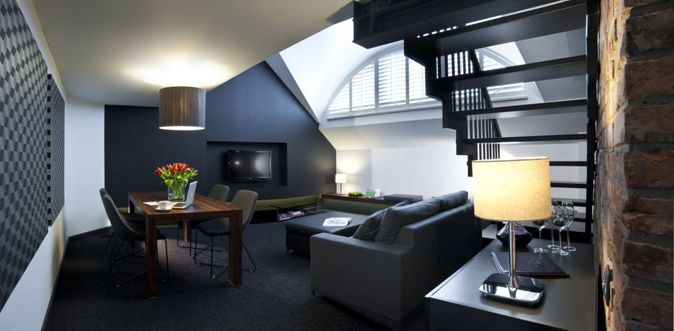 Ein modernes Wohnzimmer mit Essbereich, einer Couch, einem Fernseher und einer Treppe.