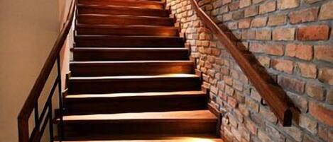 Una escalera de madera con un muro de ladrillo en un lado.