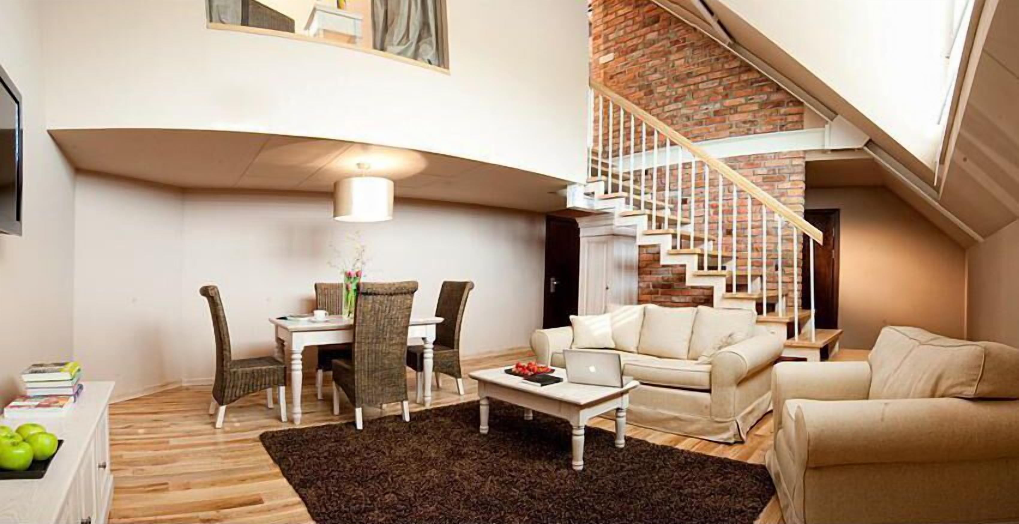 A modern living room with a dining area, a staircase, and a view of the outdoors.