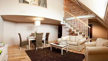 A modern living room with a dining area, a staircase, and a view of the outdoors.