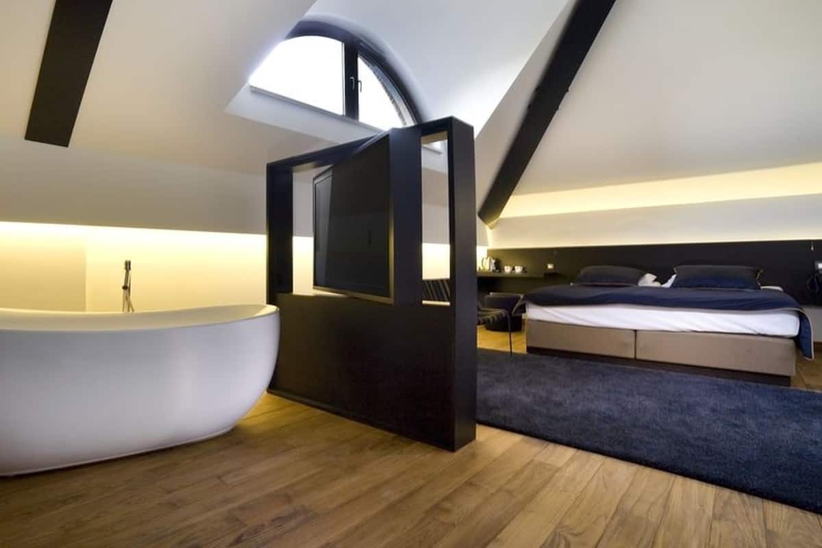Un dormitorio moderno con una bañera grande, televisión y cama.