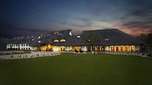 A large, modern building with multiple arched windows and a flat roof, surrounded by a well-maintained lawn. - Hotel Remes (Opalenica)