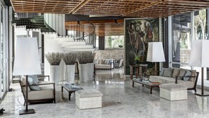 Um lobby espaçoso com uma escadaria moderna, áreas de estar confortáveis e grandes janelas que oferecem vistas do exterior.
