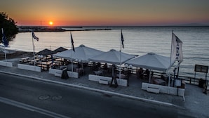 Un restaurante frente al mar con terraza, sombrillas y banderas.