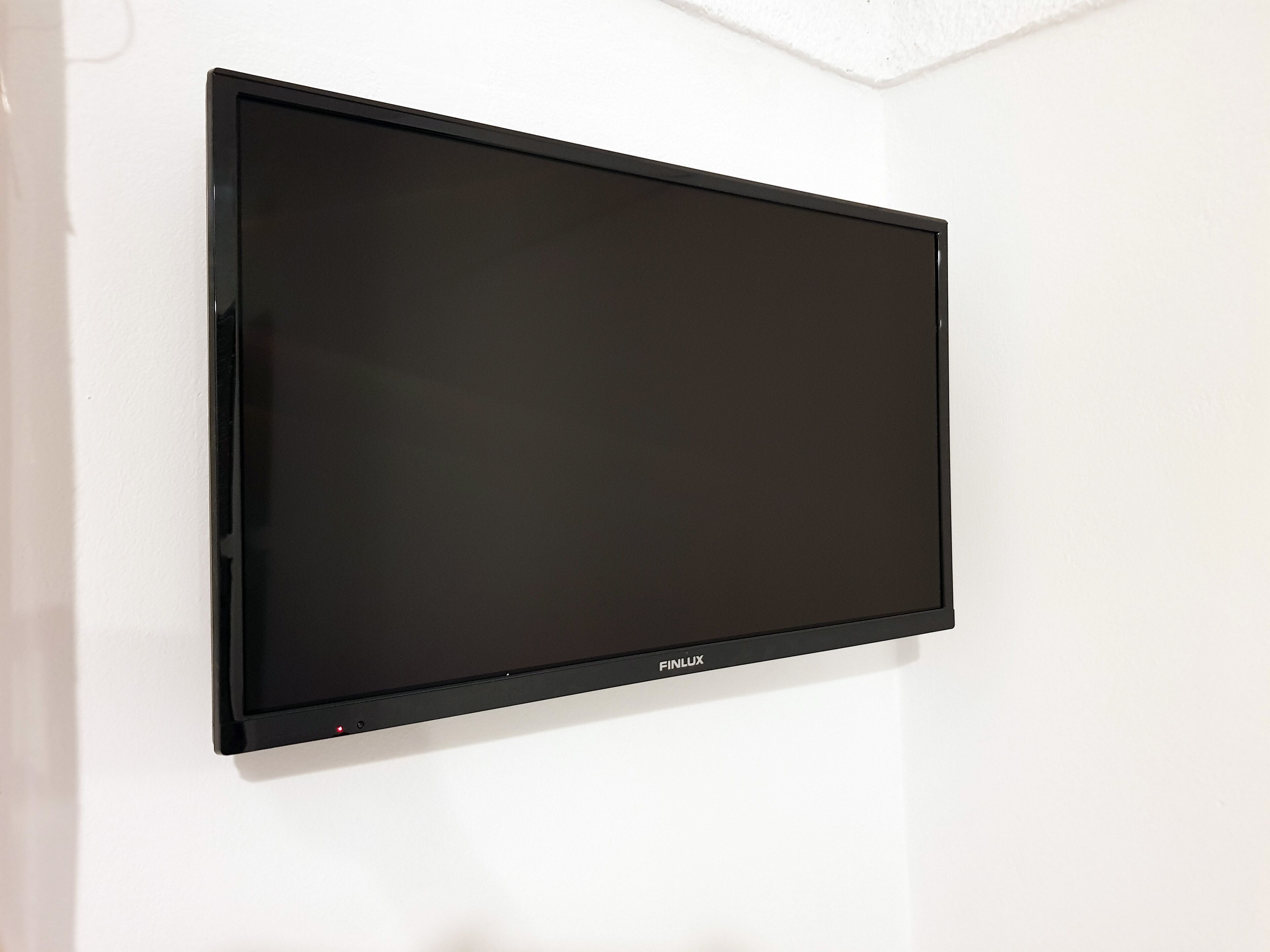 A black flat-screen TV mounted on a white wall.