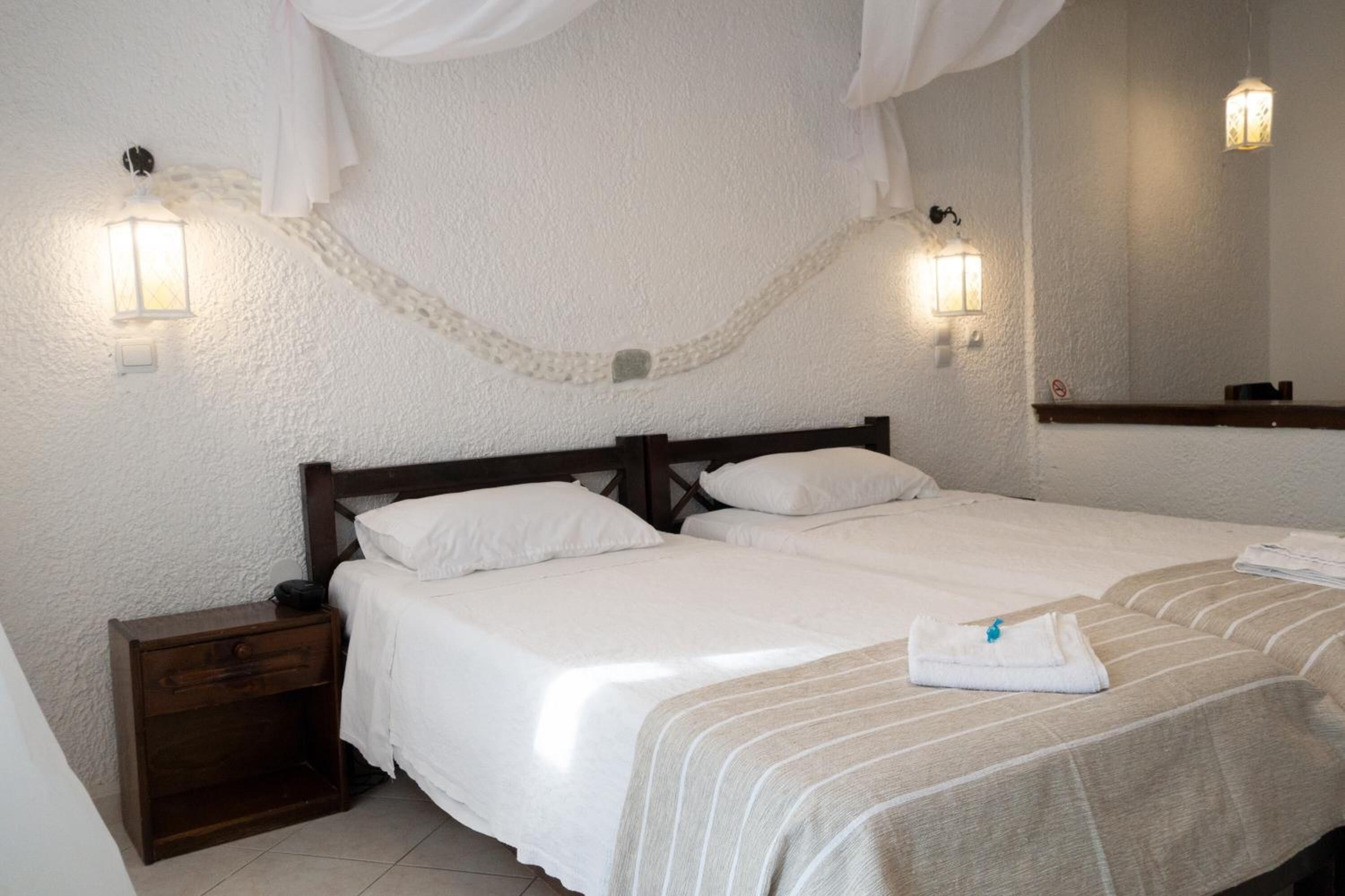 A hotel room with two beds, a nightstand, and a large mirror.