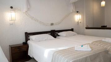 A hotel room with two beds, a nightstand, and a large mirror.