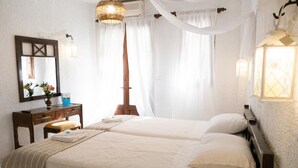 Habitación doble con dos camas, una mesita de noche de madera, un espejo y una lámpara colgante.