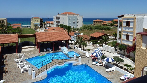 Un resort con piscina, sillones de descanso y vistas al mar.