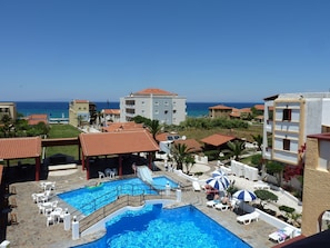 A resort with a swimming pool, lounge chairs, and a view of the sea. - Anema By The Sea Guesthouse (Samos)
