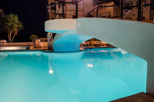 Une piscine au design architectural moderne, entourée d’espaces de détente en plein air et de palmiers.