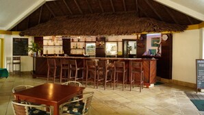 Een restaurant met rieten dak, een houten bar en een betegelde vloer.