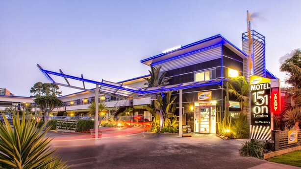A modern motel with a prominent neon sign, outdoor seating, and a covered walkway. - 151 on London Motel (Whanganui)