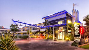 A modern motel with a prominent neon sign, outdoor seating, and a covered walkway. - 151 on London Motel (Whanganui)