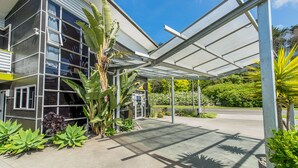 A modern building with large windows and a covered outdoor area with plants. - 151 on London Motel (Whanganui)