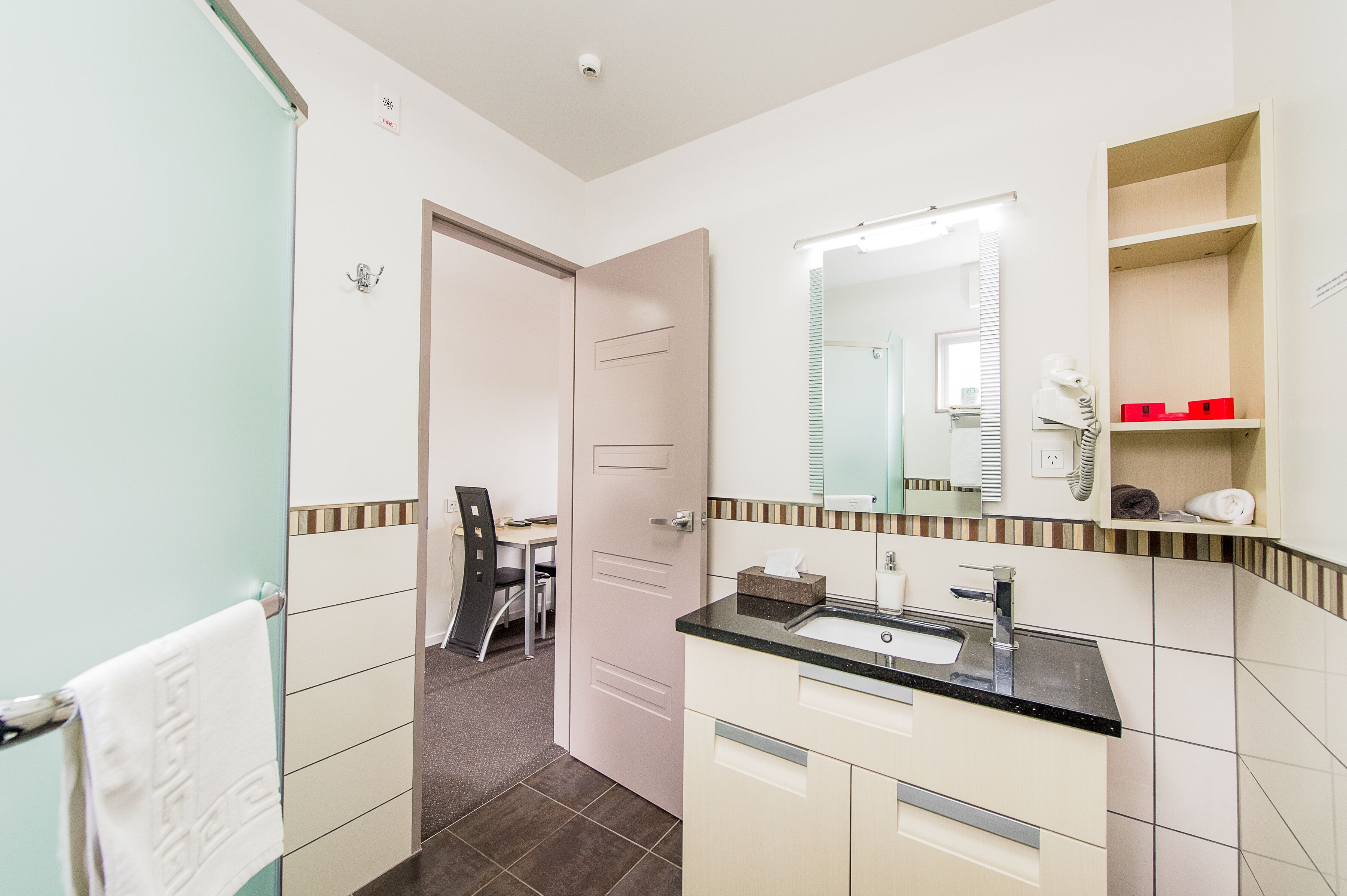 Un baño moderno con lavamanos, espejo y perchero.
