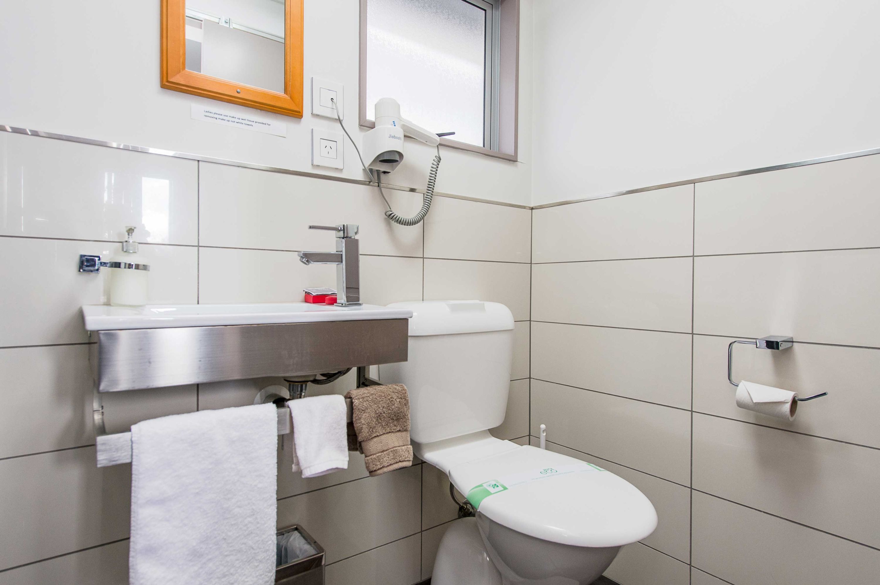 Un baño moderno con inodoro, lavabo y espejo.