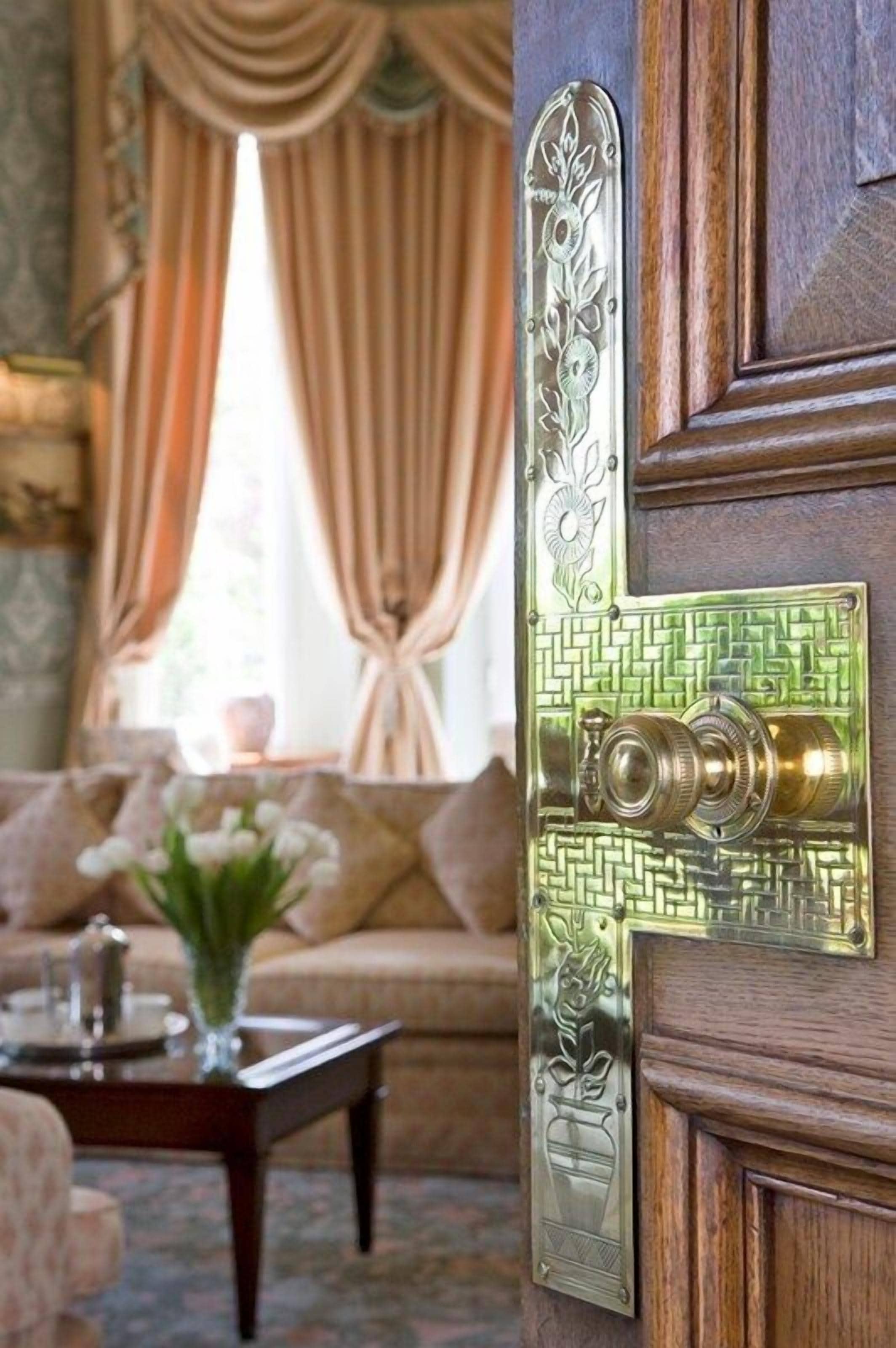 A wooden door with a brass handle and decorative panel.