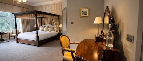 Una cama con dosel, un escritorio de madera con espejo y una silla en una habitación de hotel.