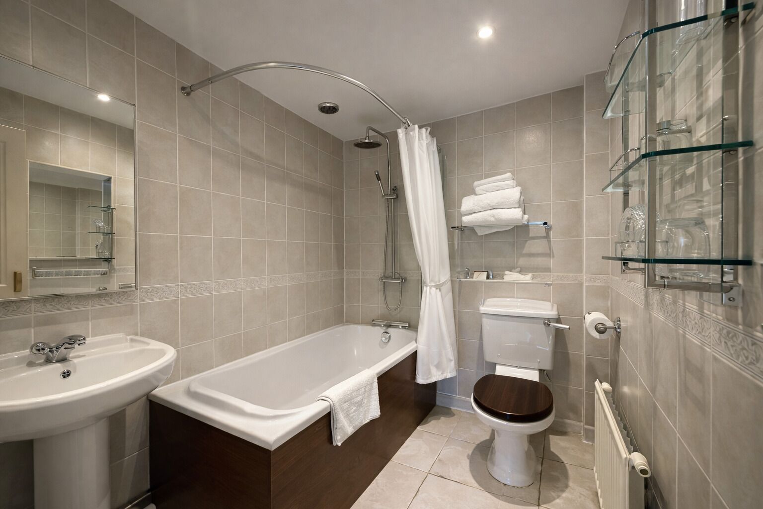 Et moderne badeværelse med badekar, vask, toilet og en brusekabine i glas.