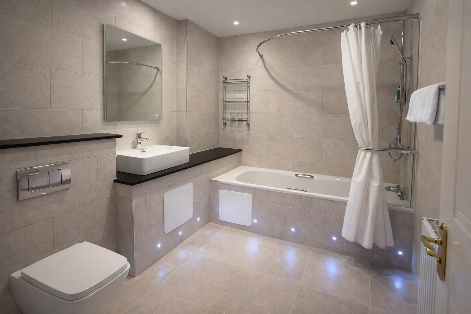 Une salle de bain moderne équipée d’une baignoire, d’une douche, de toilettes et d’un lavabo.