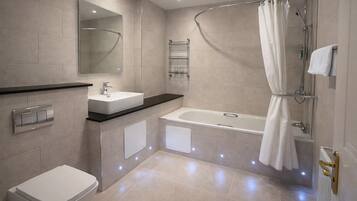 Un baño moderno con bañera, ducha, inodoro y lavabo.