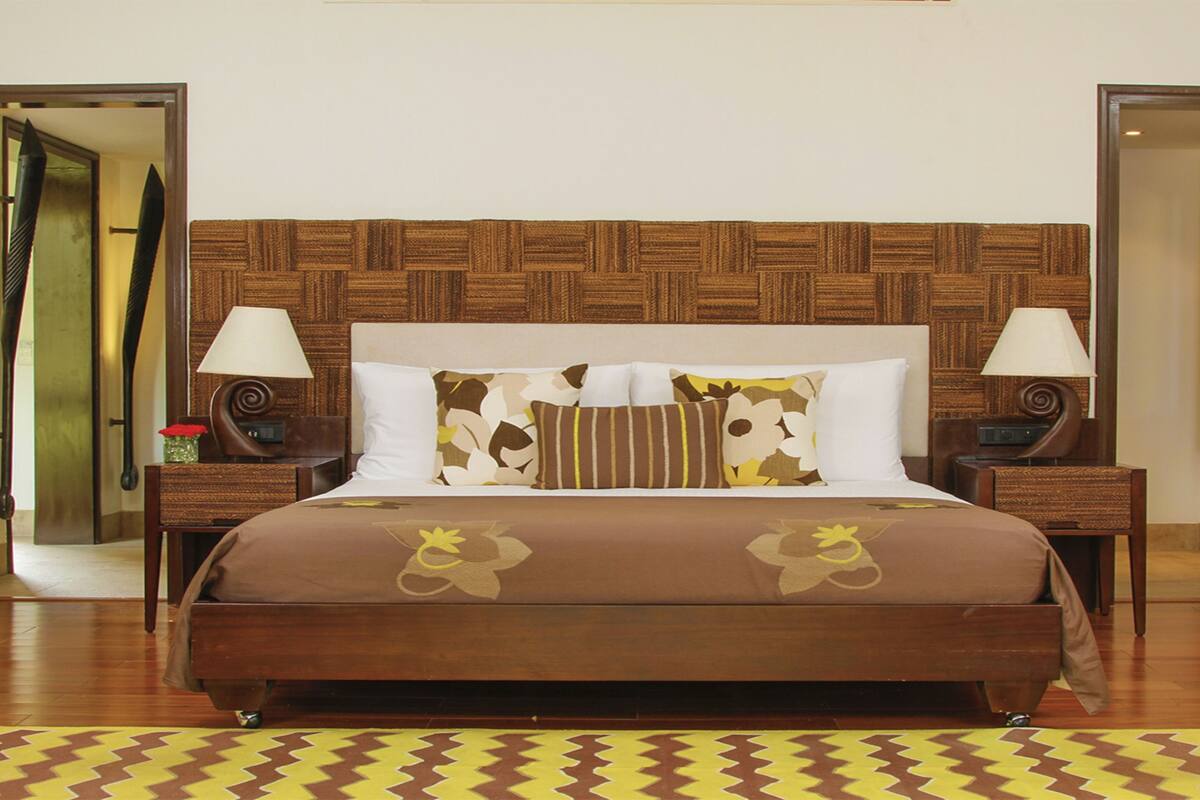 Een hotelkamer met een groot bed, twee nachtkastjes met lampen, een houten hoofdbord en een kamerkleed met patroon.
