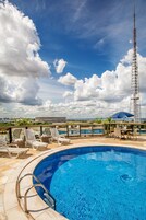 Una piscina al aire libre, sombrillas, sillones reclinables de piscina