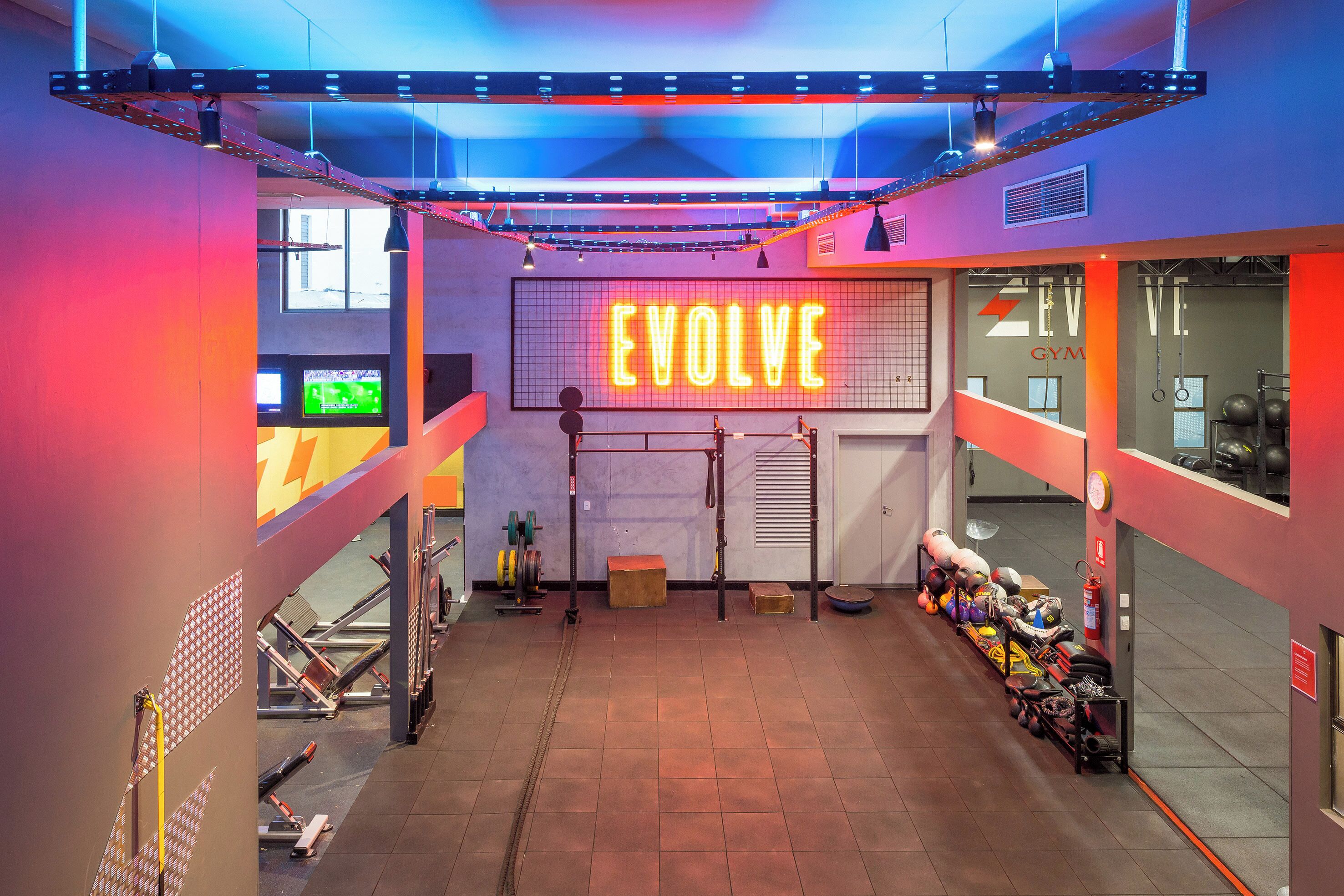 A gym with a neon sign reading "EVOLVE" and exercise equipment.
