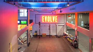 A gym with a neon sign reading "EVOLVE" and exercise equipment.