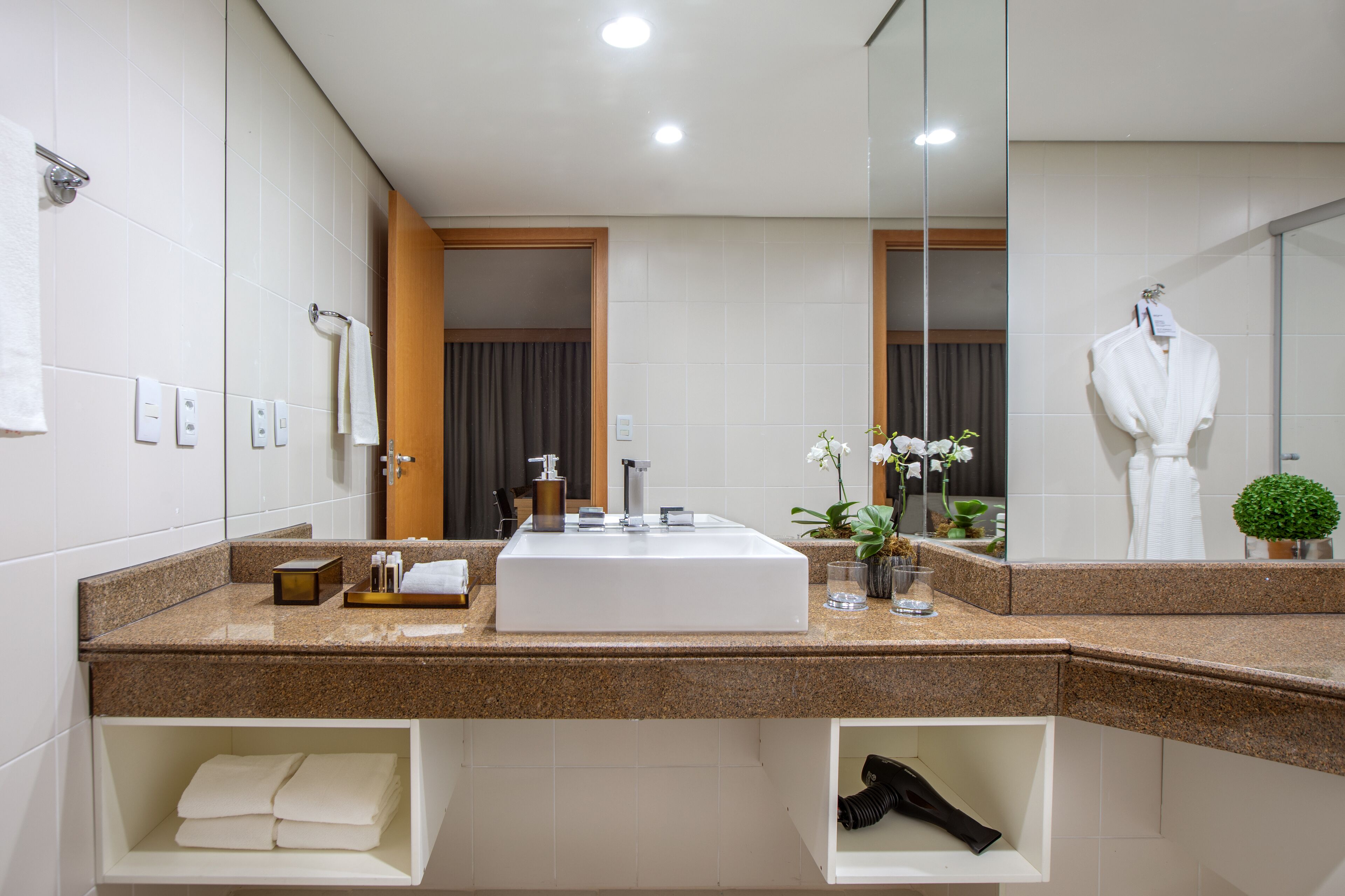 Un baño moderno con un lavamanos grande, un espejo y una bata colgada en la pared.