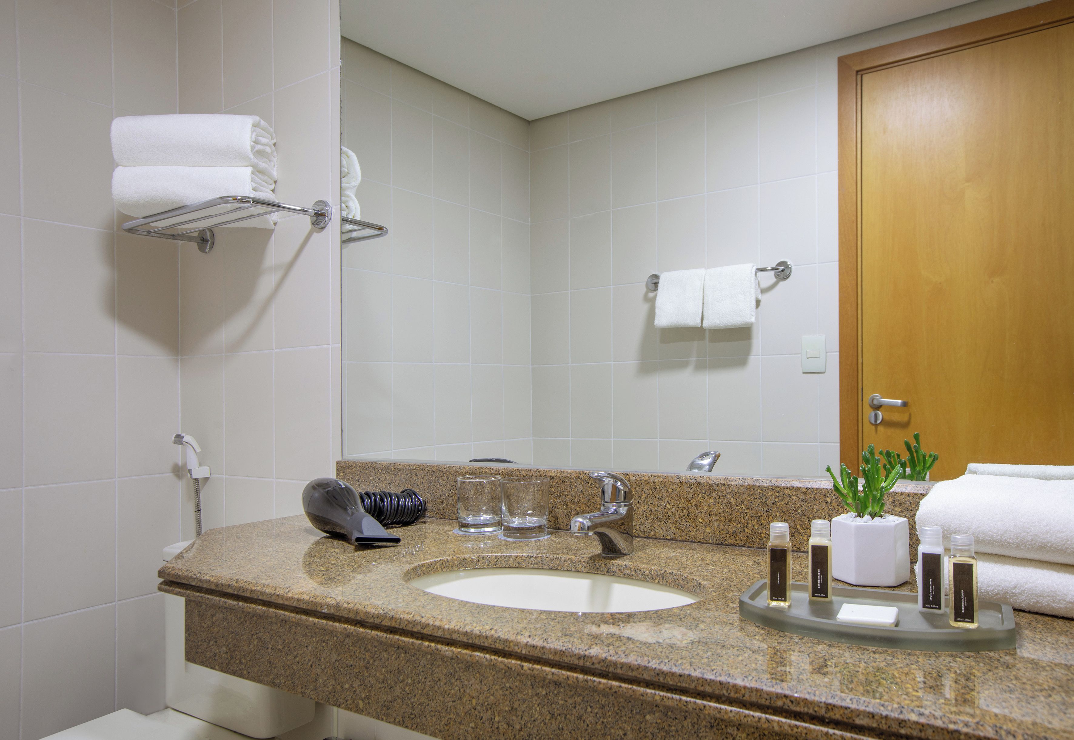 A bathroom with a granite countertop, a sink, a mirror, a towel rack, and a door.