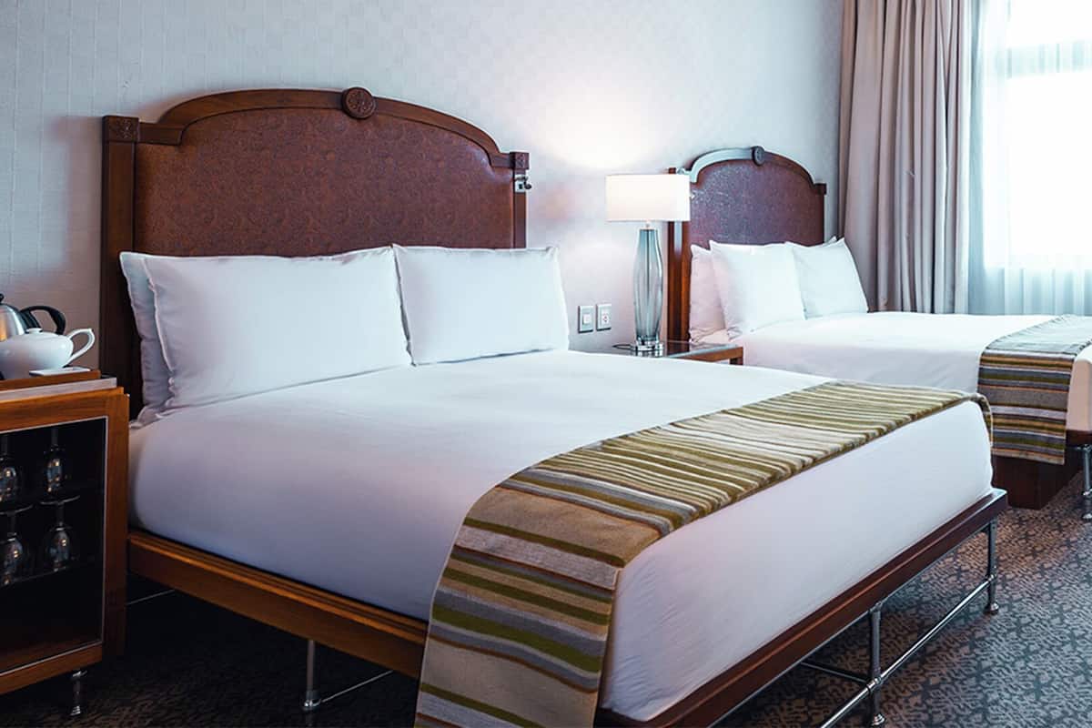 Habitación de hotel con dos camas, un escritorio, una silla y una mesita de noche.