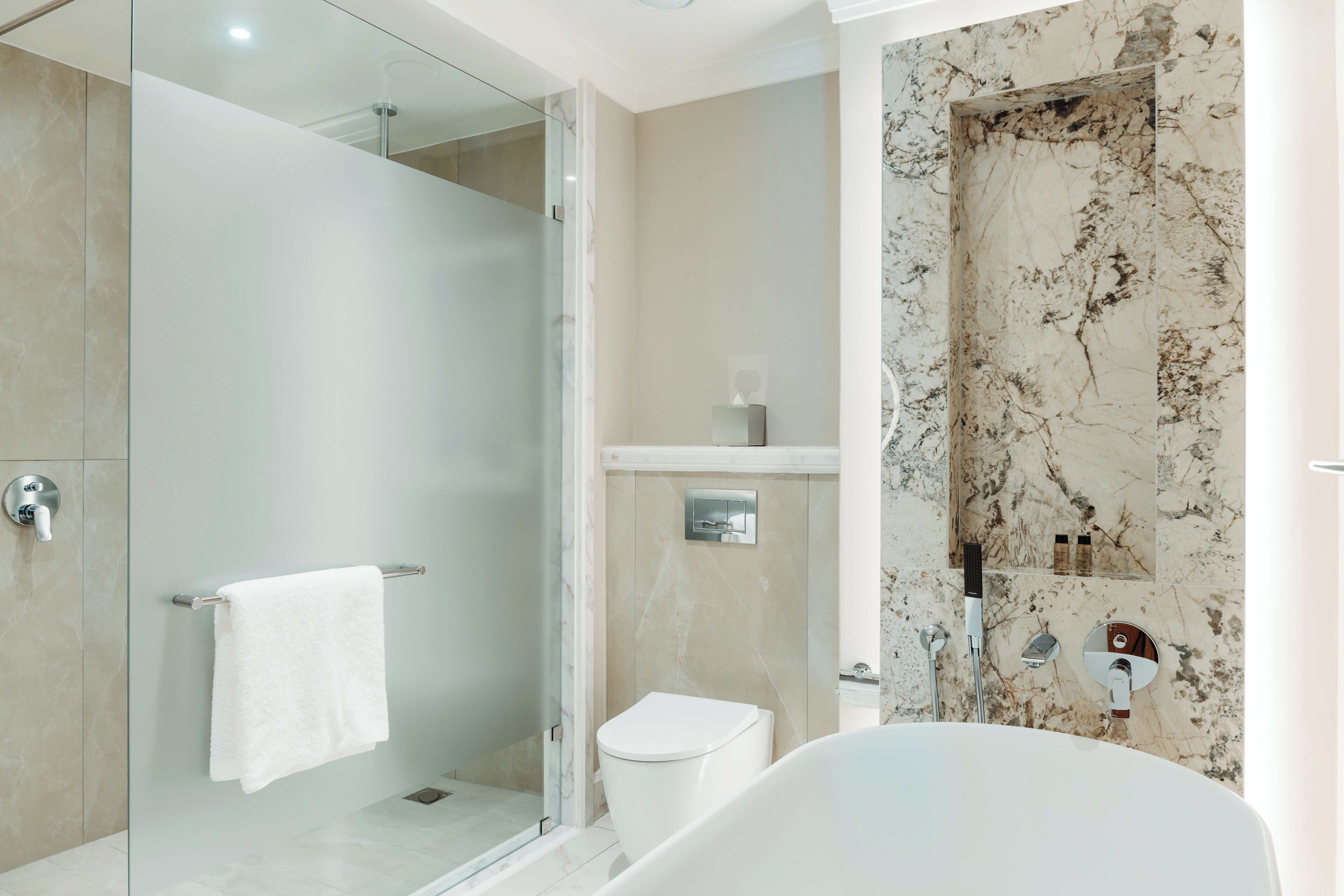 A modern bathroom with a glass-enclosed shower, a white toilet, and a freestanding bathtub.